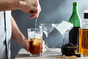 Bartender mixing cocktail with mixing spoon.