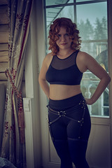 Young redheaded woman in playful stockings with leather harness
