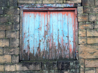 decaying blue painted shutters with rotting wood in a derelict abandoned house