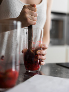 Person squeezing berries in the glass