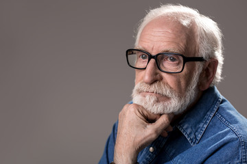 Portrait of tranquil white-headed gaffer staring and dreaming. Copy space in left side. Isolated on grey background