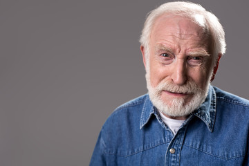 So sorry. Portrait of old bearded man looking at camera with pity. Copy space in left side. Isolated on grey background