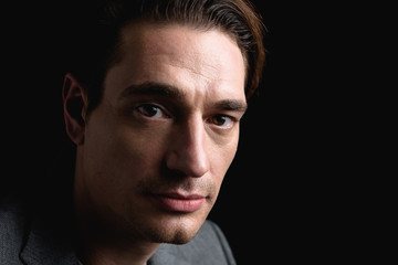 Melancholy. Close-up portrait of young attractive sad man is standing and looking at camera thoughtfully. Isolated on black background