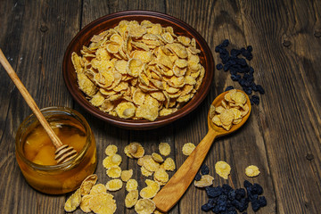 Corn flakes in a bowl on a table with milk and honey for a background. Breakfast, healthy food. Selective focus.