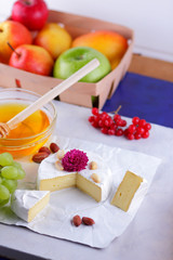 Cheese, camembert on white background, honey, red berries, apples, pears, cheese with green grapes, peanuts, pink flower, minimalism, healthy food, French breakfast
