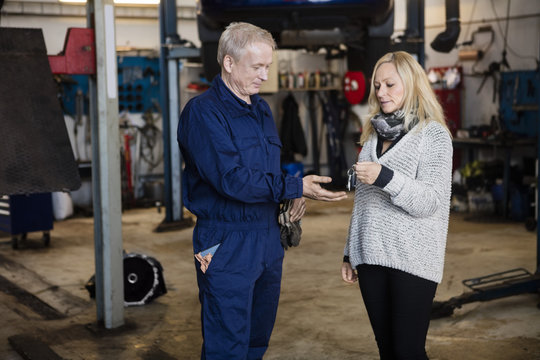 Customer Handing Car Key To Mechanic In Garage