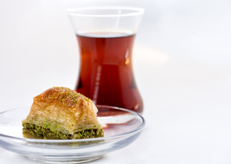 Baklava with pistachio and turkish cup of tea on a white background