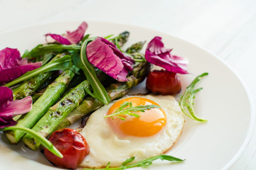 Fried egg and roasted fresh asparagus in black plate
