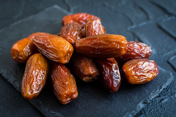 Dried dates on black stone background