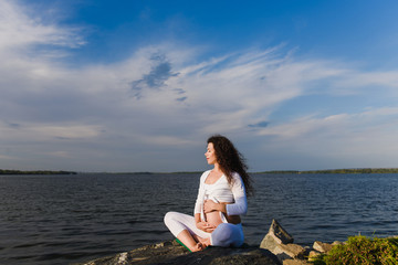 Fototapeta na wymiar Meditating pregnant woman in lotus position.