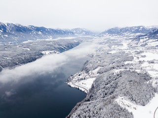 Snow covered winter landscape, cloud over a large lake.