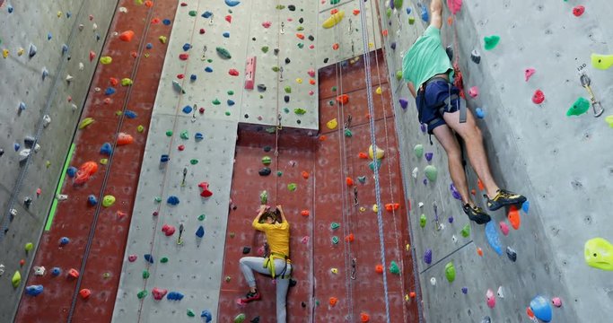 Man and woman practicing rock climbing in fitness studio 