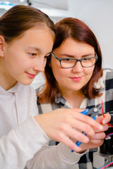 Two teen working on CNC machinery.