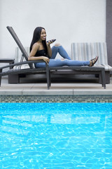 Black female on a speaker phone call in a hotel resort.  She is working while on vacation or dictating reminders on a voice assistant on her cellphone.