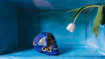blue mexican skull looking at a tulip