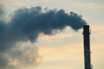 Pipe with smoke on a background of the sky close-up, with copy space.