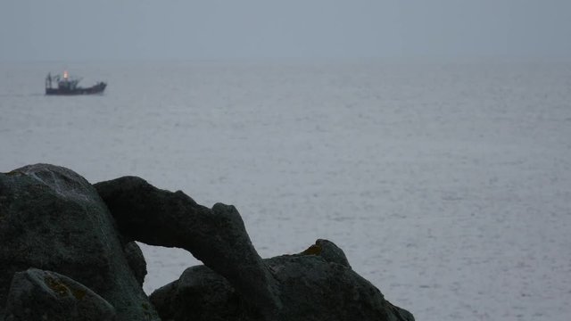 A rock like an animal, far-off a fishing boat crossing the frame, with his lights, dusk - Rocher en forme d'animal au loin un bateau de p&ecirc;che traverse le plan, on voit ses feux, crepuscule