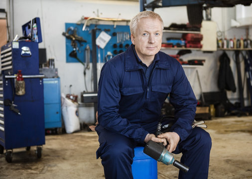 Confident Mechanic Holding Drill Tool In Garage