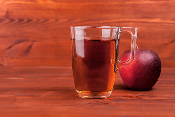 apple juice in a glass and apples on wooden background .