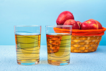 two glasses  of apple juice and red apples on wooden background .