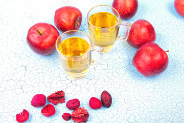 two glasses  of apple juice and red apples on wooden background .