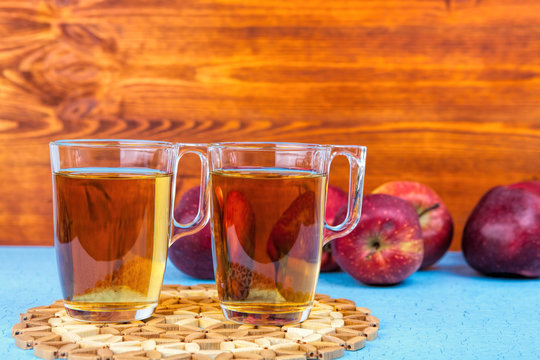 two glasses  of apple juice and red apples on wooden background .