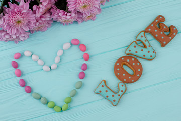 Letter cookies for Valentines Day. Shape of heart from candies. Composition for Valentines Day from flowers and sweets.