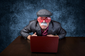 Alter Senior sitzt mit Brille vor einem Computer und versucht zu recherchieren