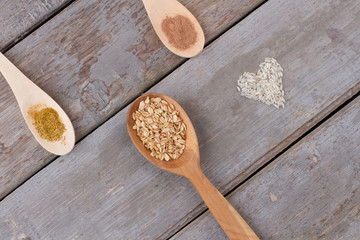 Wooden spoon with oat flakes. Rice in a shape of heart on old wooden background, top view.