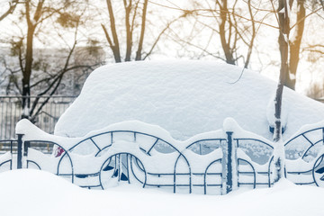 Car on a street covered with big snow layer.