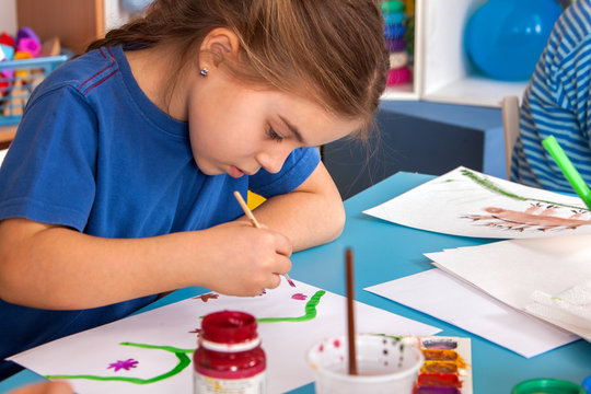 Small students painting in art school class. Child drawing by paints on table. Kid on balloons background. Psychological child test in kindergarten.