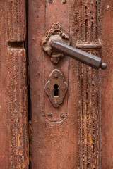 Old brown wooden door with worn paint and metal handle
