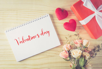 Gift box white bow ribbon and heart valentine text with notebook .on wood table background top view, february of valentine's day in concept.