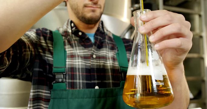 Brewer checking beer with hydrometer 