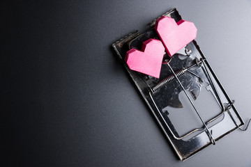 Mousetrap use box red heart shape as bait on black background with copy space.Valentine's Day, Day of love.