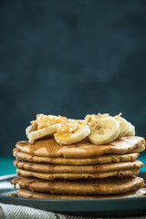 Pancakes topped with fresh banana and walnuts.