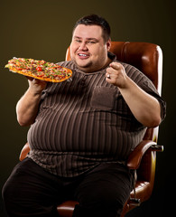 Fat man eating fast food and offers great pizza to customers . Male treats chic junk meal to...