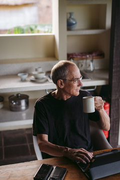 Mature man in his 60's working and traveling with tablet in trop