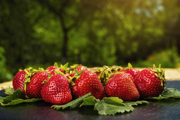 strawberries on stone table in natural background, delicious first class organic fruit as a concept of summer vitamins