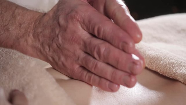 Osteopath doing manipulative massage on female abdomen. Man hands massaging female.Therapist applying pressure on belly. Spa centre concept