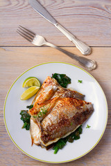 Dorado or dorada fish fillet with spinach, thyme and lime. View from above, top, vertical