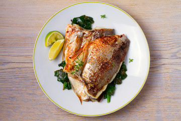 Dorado or dorada fish fillet with spinach, thyme and lime. View from above, top, horizontal