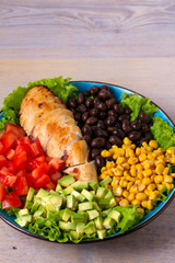 Chicken dish with nutritious selection of vegetables: avocado, beans, tomatoes and sweet corn. Chicken breast salad