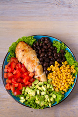 Chicken dish with nutritious selection of vegetables: avocado, beans, tomatoes and sweet corn. Chicken breast salad