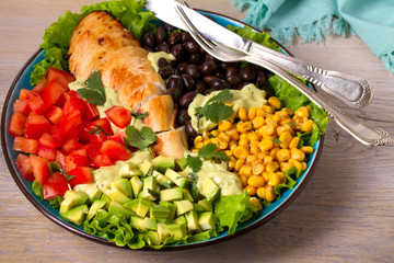 Chicken dish with nutritious selection of vegetables: avocado, beans, tomatoes and sweet corn. Chicken breast salad