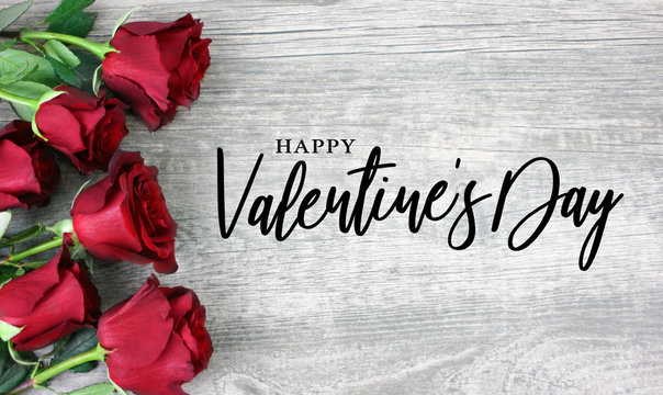 Happy Valentine's Day Calligraphy with Red Roses Over Rustic Wood Background