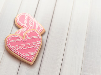 Two heart shaped cookies decorated with pink royal icing.