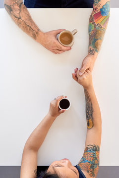 Mixed-race couple with tattoos holding hands