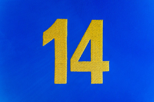 Closeup of woven fourteen 14 number on cloth against bright vibrant blue background