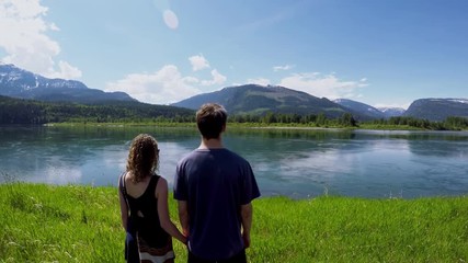 Couple watching beautiful lake surrounded by mountain range 